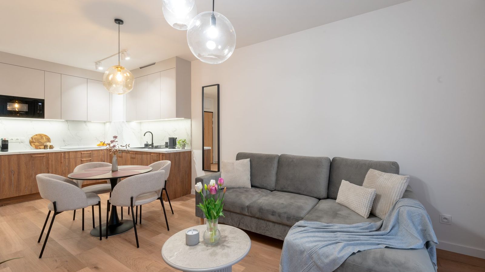 Salon z aneksem kuchennym i stołem jadalnym w apartamencie Polna 23A/46