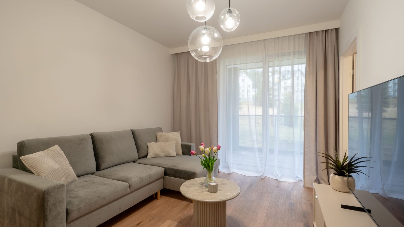 Salon z narożną sofą i wyjściem na balkon
